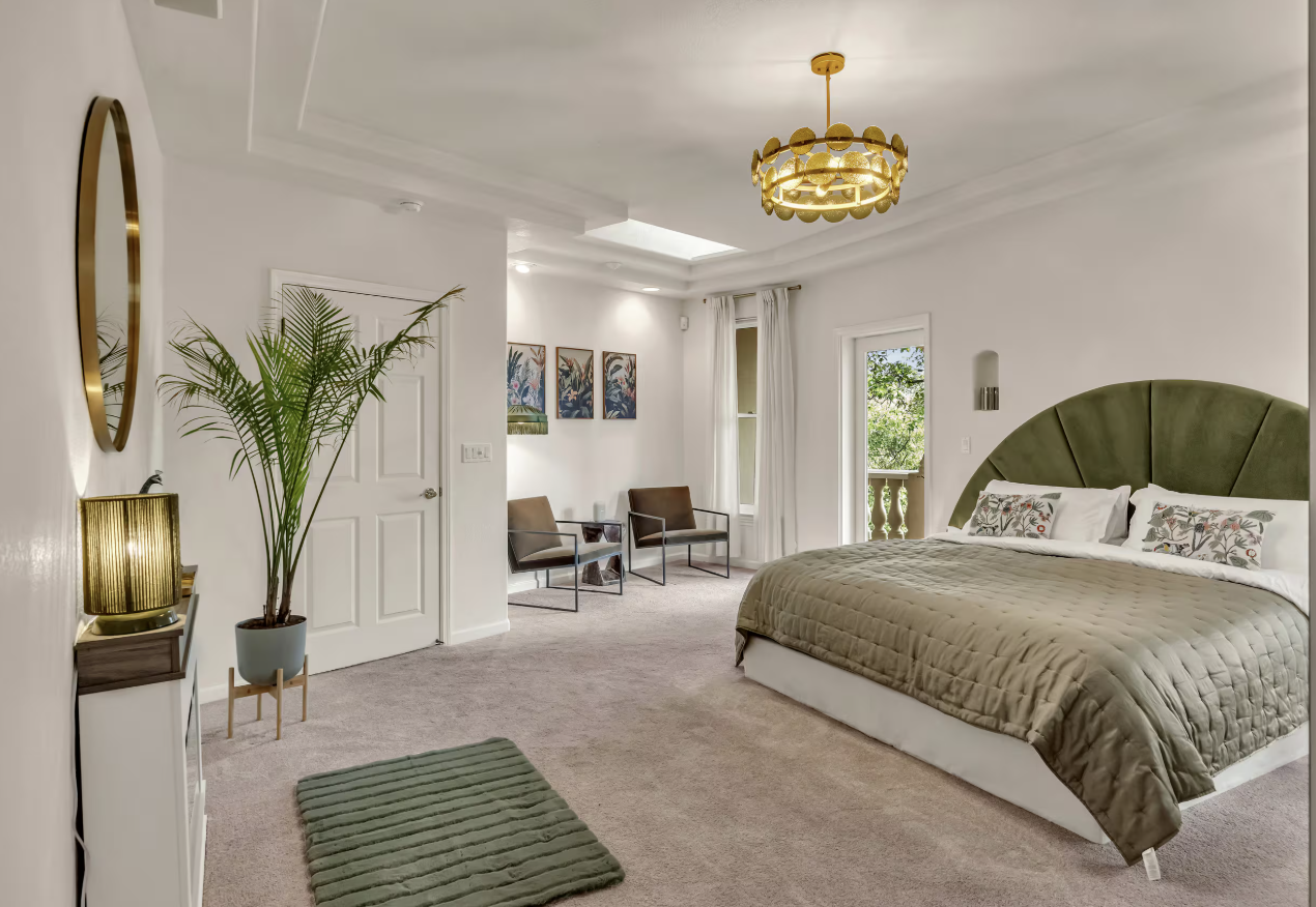 Spacious bedroom with green velvet headboard and sitting area