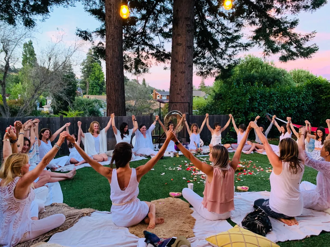 Lisa with a circle of women at sunset, hands raised in celebration
