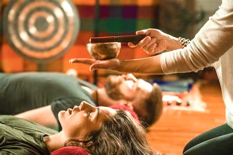 Sound bath ceremony with singing bowl held over resting guests